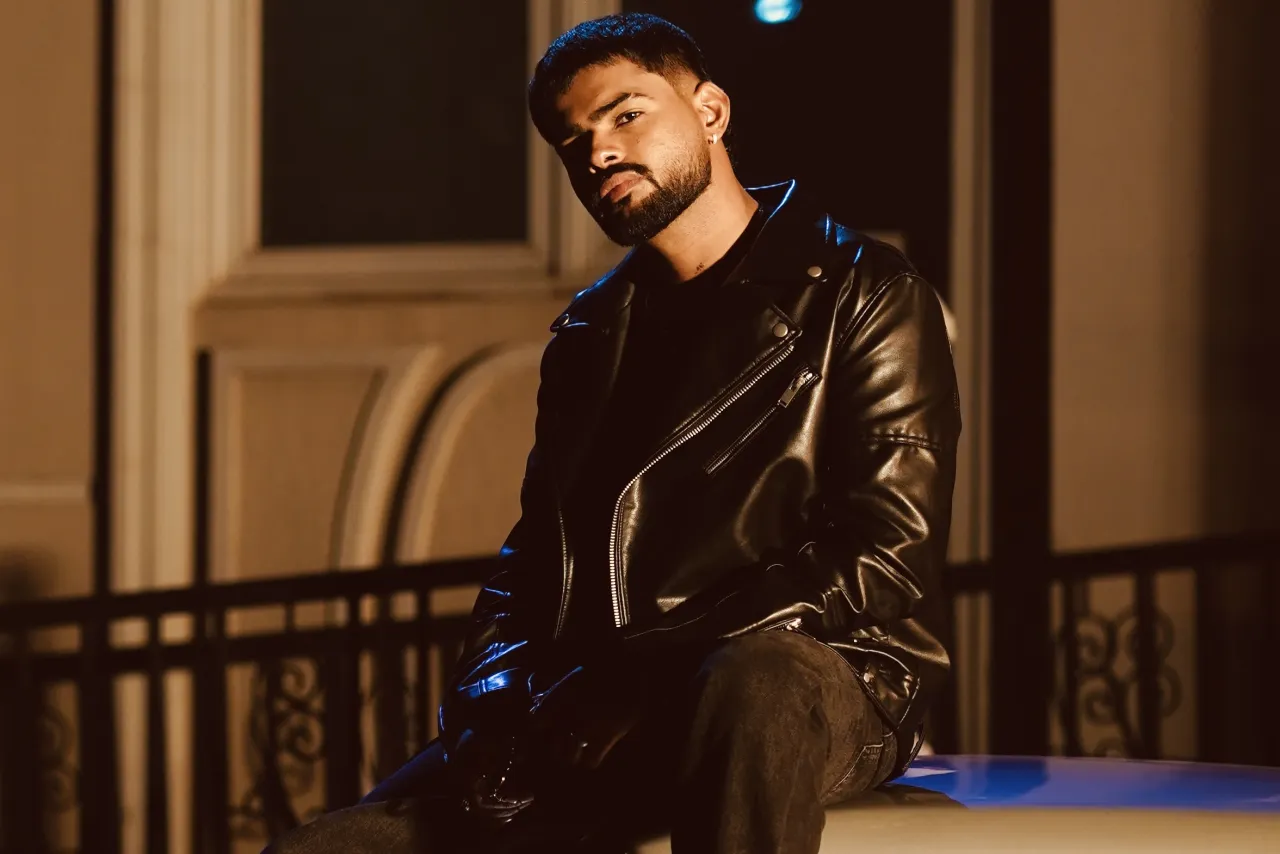 Badal in a black leather jacket, seated outdoors at night under warm light